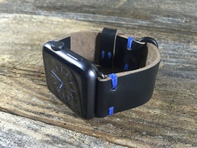 Black apple watch with black leather band featuring blue stitching