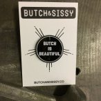 a black and white circle lapel pin says "butch is beautiful" and is mounted on a white piece of cardstock that reads BUTCH & SISSY with the website BUTCHANDSISSY.CO